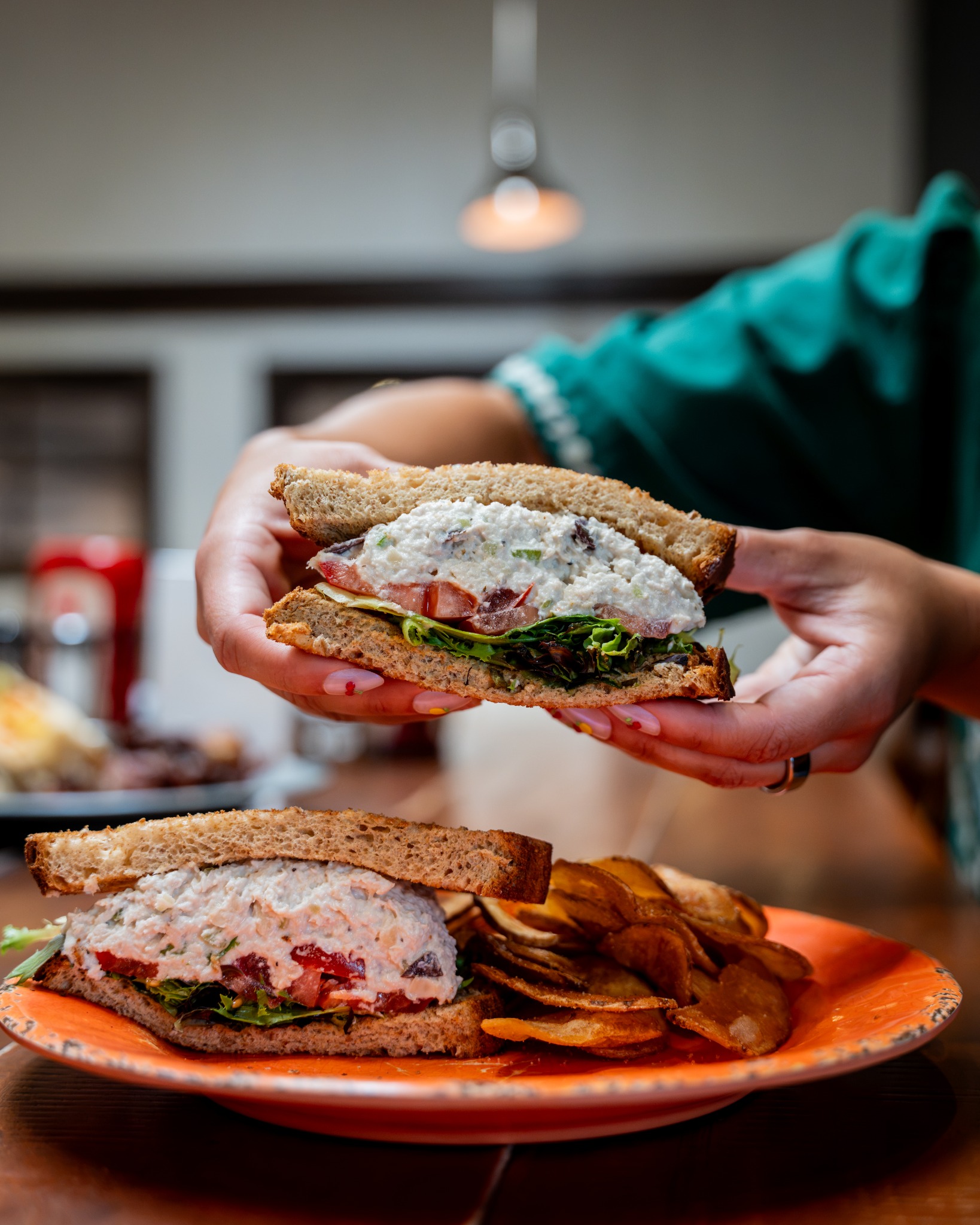 Guest holding a Sonoma chicken salad sandwich at Pioneer